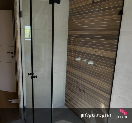 מקלחון פינתי מזכוכית שקופה עם פרופיל וצירים בצבע שחור